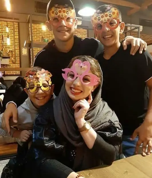 تصویری شاد از مشتریان پیتزا سیب با عینک‌های جشن پیتزایی و قلب‌شکل، لحظات مفرح و خاطره‌انگیز را در محیط گرم رستوران نمایش می‌دهد.