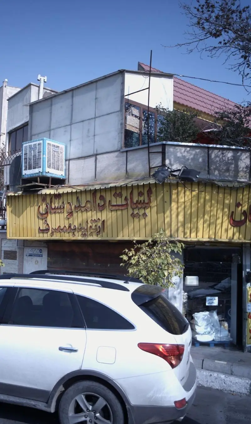 تصویری از نمای بیرونی فروشگاه لبنیات دوستان با تابلوی زرد رنگ، مکانی مناسب برای خرید انواع محصولات لبنی و سنتی تازه.