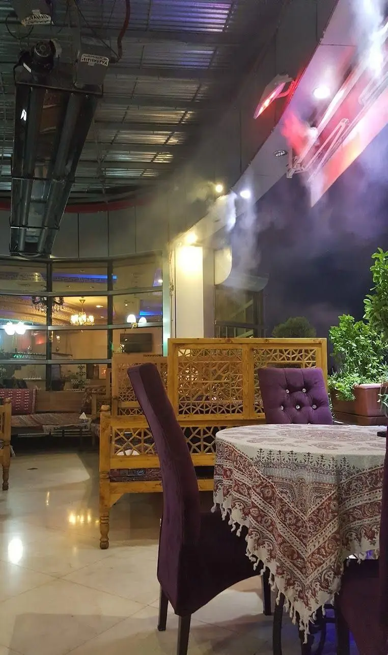 فضای دلنشین شبانه رستوران و سفره خانه مانلی با دکوراسیون سنتی، میز و صندلی‌های راحت، و مه خنک محیط.