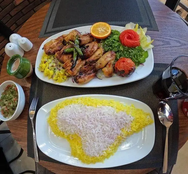 نمایی از سرو غذای ویژه رستوران ضیافت: جوجه کباب مجلسی با چلو زعفرانی و سفید، سالاد تازه. طعم بی نظیر غذای ایرانی را تجربه کنید.