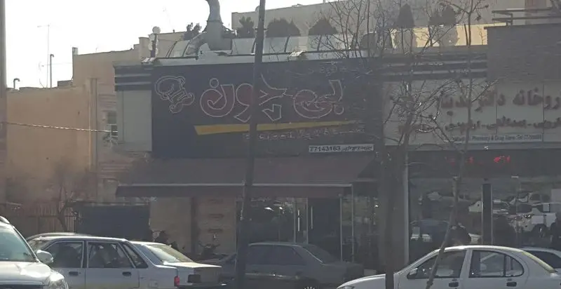 فست‌فود بی‌چون: نمای بیرونی رستوران با تابلوی بزرگ و لوگوی سرآشپز. ارائه دهنده بهترین غذاهای فوری و ساندویچ‌های تازه در محیطی دلنشین.