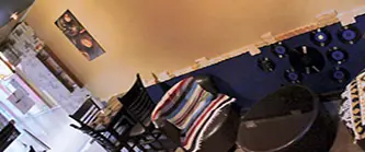 تصویری از فضای دلنشین و دکوراسیون داخلی کافه آرام، شامل میز و صندلی‌های چوبی، دیوارهای آبی و بژ با تزئینات هنری. محیطی آرام و ایده‌آل.