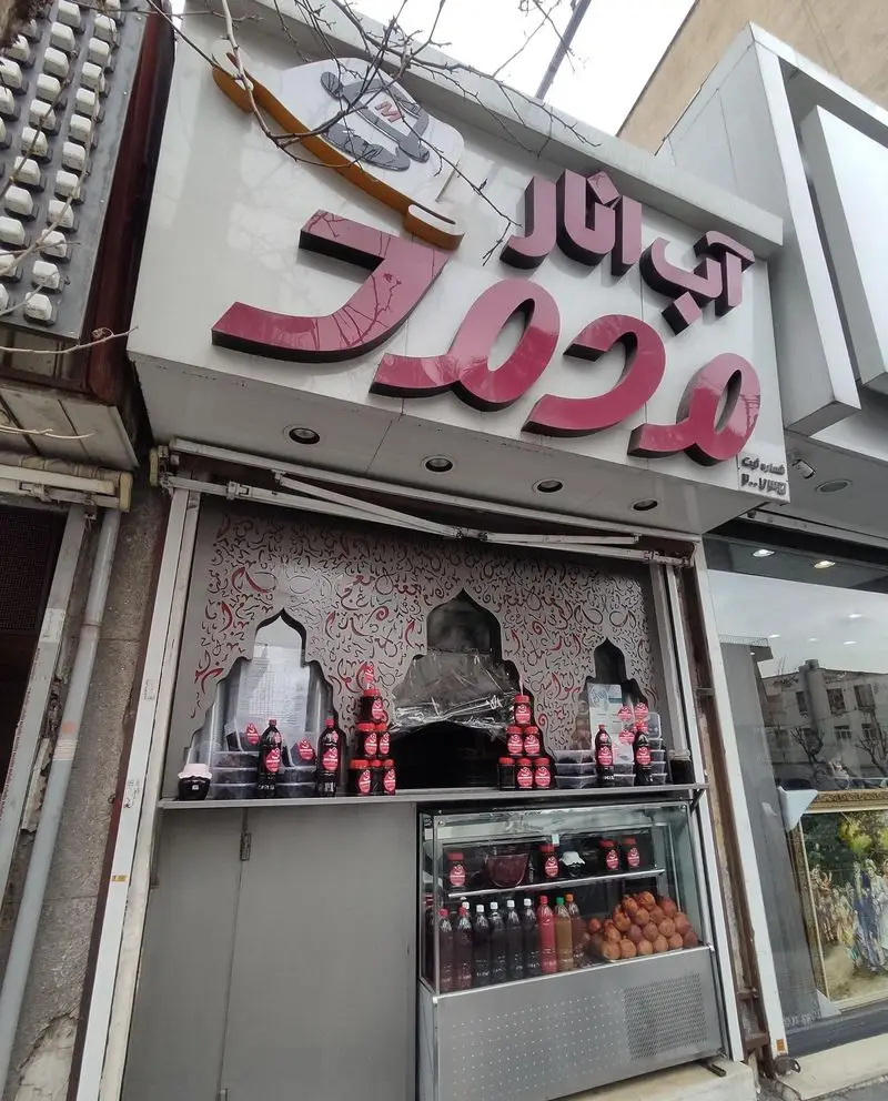 تابلوی مغازه آب انار محمد، آبمیوه فروشی تخصصی انار، با نمایش بطری‌های آب انار طبیعی و میوه تازه انار در ویترین.