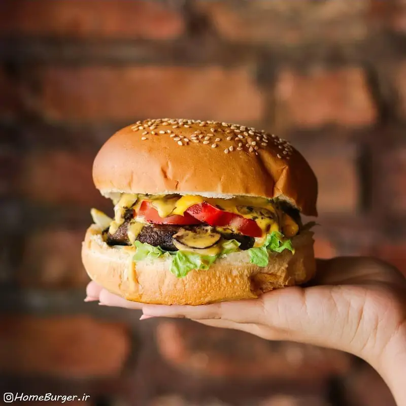 یک همبرگر لذیذ و پرملات از هوم برگر، با پنیر، قارچ، کاهو و گوجه، مناسب برای طرفداران ساندویچ‌های خوشمزه و باکیفیت.