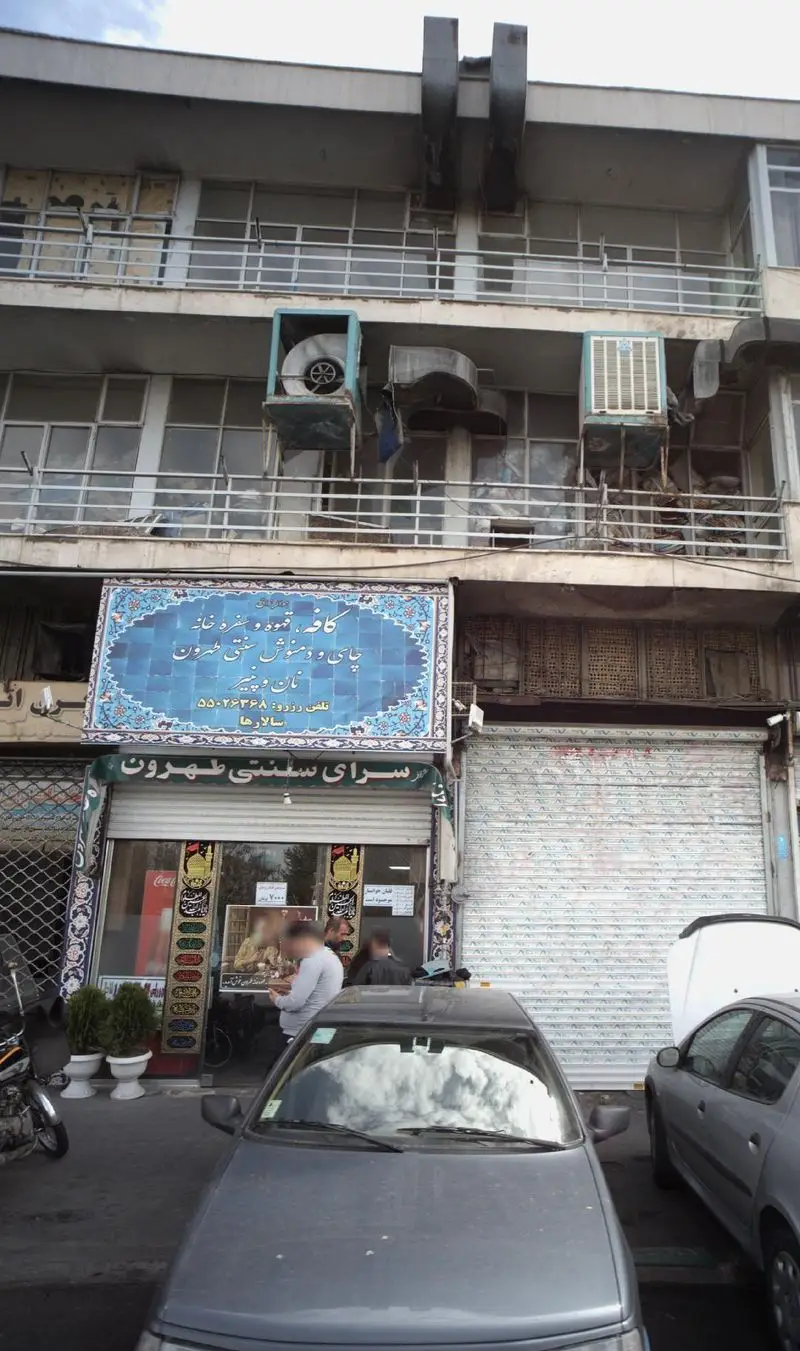 نمای بیرونی سرای سنتی طهرون در تهران، کافه و سفره خانه سنتی با چای، قهوه و دمنوش، تابلوی آبی رنگ و مشتریان.