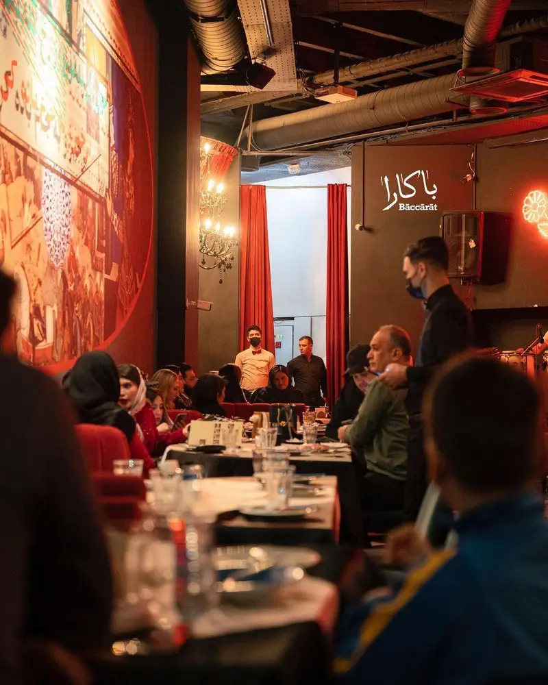 نمایی از فضای داخلی لوکس رستوران لبنانی باکارا لانژ، مهمانان در میزها نشسته و از غذا لذت می‌برند. دیوارنگاره هنری و نورپردازی جذاب.