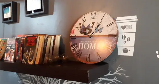محیط دنج و زیبای کافه قرار: قفسه کتاب‌های متنوع، ساعت دیواری پروانه‌ای، دکور جذاب قهوه و فضایی ایده‌آل برای مطالعه و قرار.