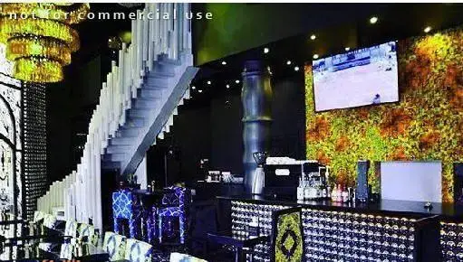 فضای داخلی شیک و مدرن کافه رستوران بارزیل با لوستر درخشان، پله‌های سفید منحصر به فرد، میز بار مجهز و دیوارپوش گیاهی چشم‌نواز.