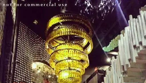 دکوراسیون داخلی خاص و جذاب کافه رستوران بارزیل با لوستر بزرگ و هنری از بطری و دیوارهای دکوراتیو و پله‌های مدرن.