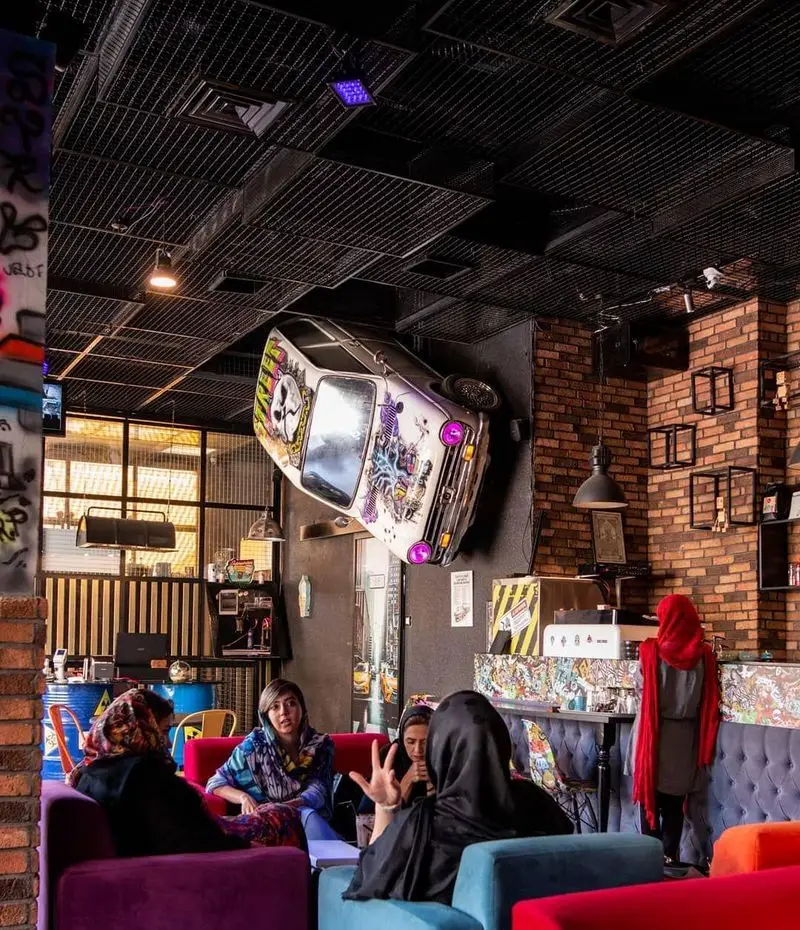 فضای داخلی کافه خیابون با طراحی خاص، سقف مشبک، دیوار آجری و ماشین گرافیتی معلق، پاتوقی ایده‌آل برای دوستان و جوانان.