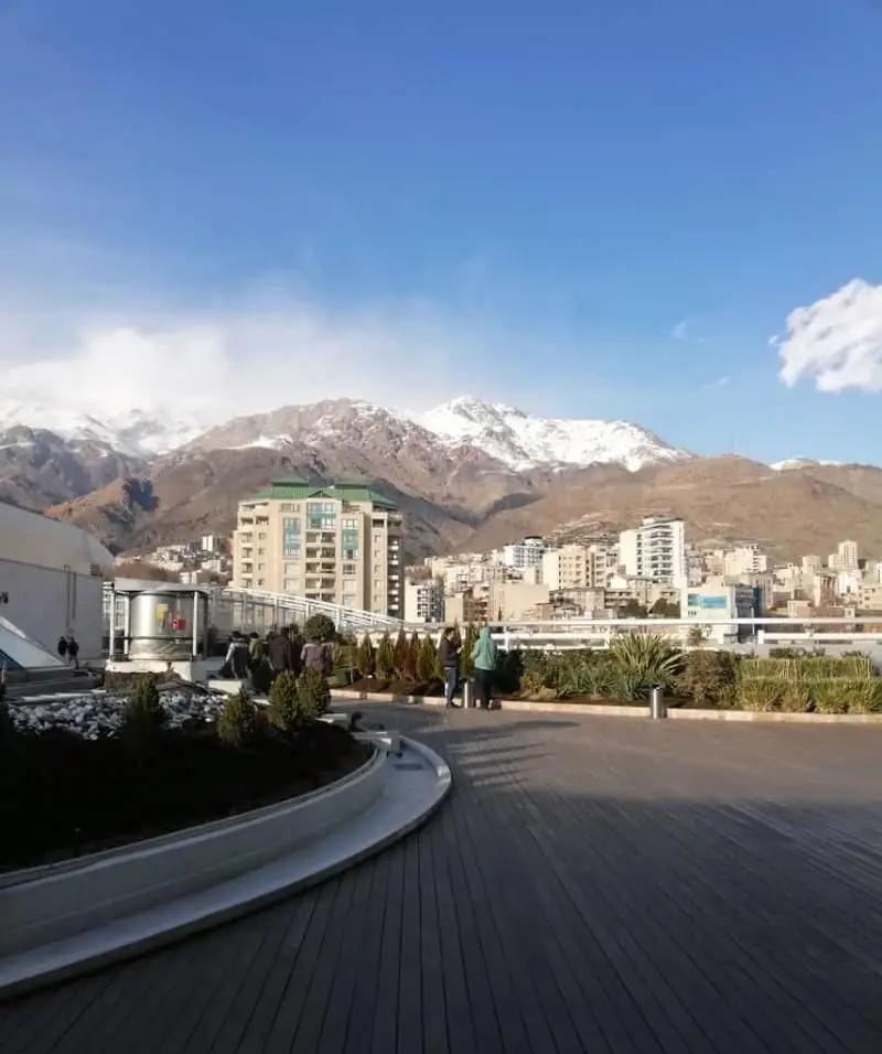 نمای دلنشین تراس کافه فلورین با چشم‌انداز خیره‌کننده کوه‌های پوشیده از برف البرز و بافت شهری تهران. مکانی مدرن و آرام برای دورهمی.