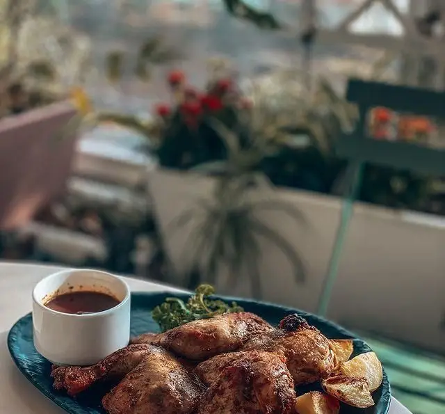 غذای اصلی لذیذ کافه فلورین: جوجه بریان کامل با سس مخصوص و سیب زمینی، در فضای سبز کافه.