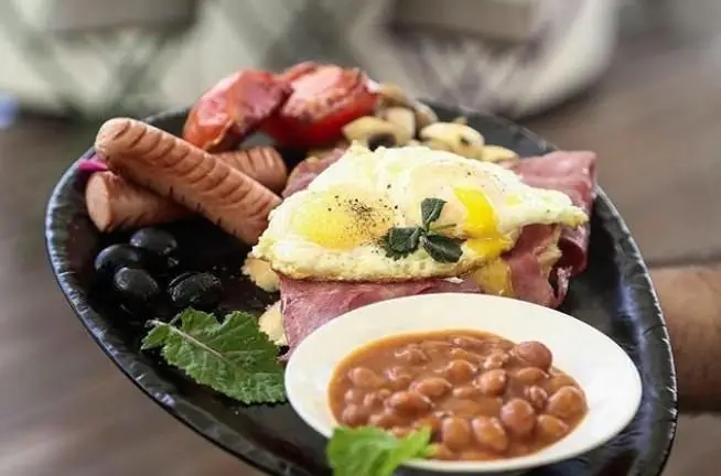 صبحانه ویژه کافه فلورین: املت عسلی، سوسیس، بیکن، قارچ، گوجه، زیتون سیاه و لوبیا پخته، غذای لذیذ و پرانرژی برای روز شما.