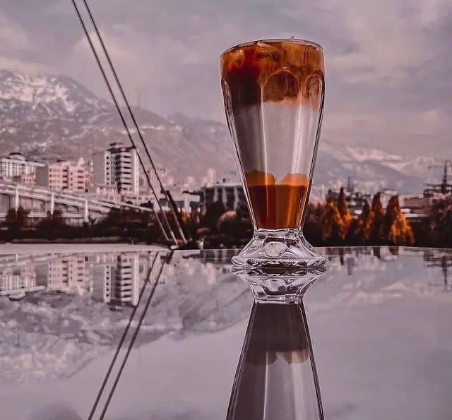 تصویری جذاب از آیس لاته کافه فلورین با چشم‌انداز خیره‌کننده شهر و کوهستان‌های پوشیده از برف. لحظاتی به‌یادماندنی.