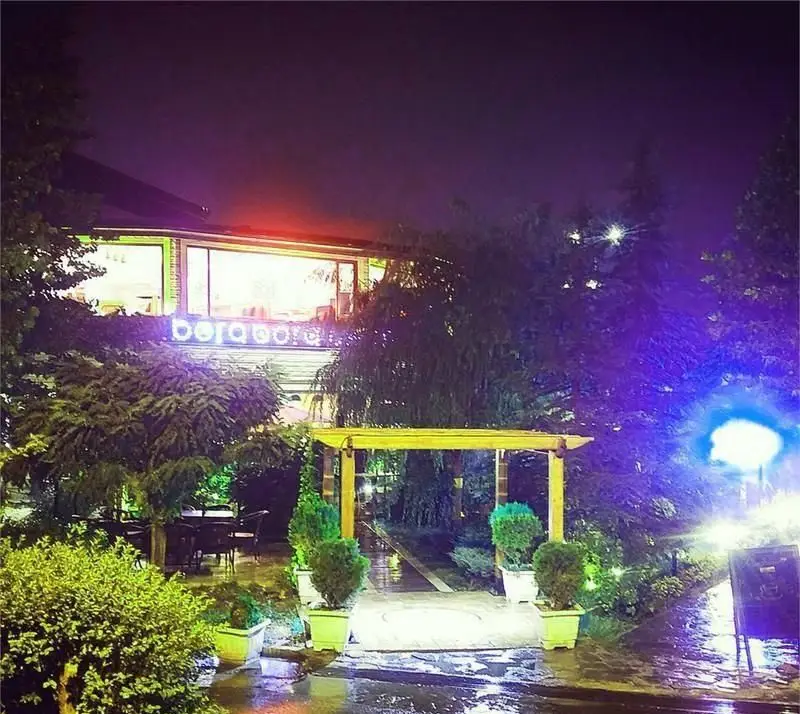 نمای شبانه و جذاب کافی شاپ بورا بورا با نورپردازی زیبا، فضای سبز دلنشین و ورودی دنج و دلپذیر برای مشتریان.