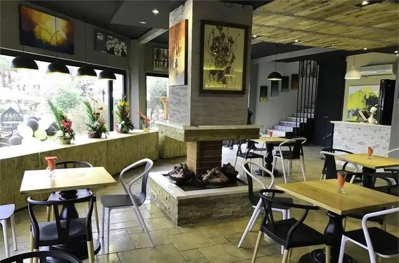 فضای داخلی دنج و مدرن کافی شاپ بورا بورا با میز و صندلی‌های شیک، پنجره‌های بزرگ، آثار هنری خاص و تزئینات گیاهی.