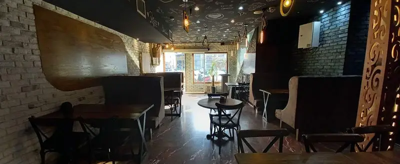 فضای داخلی مدرن و دنج رستوران ایتالیایی ژولی با دیوارهای آجری، سقف طرح‌دار و مبلمان شیک، محیطی ایده‌آل برای غذا.