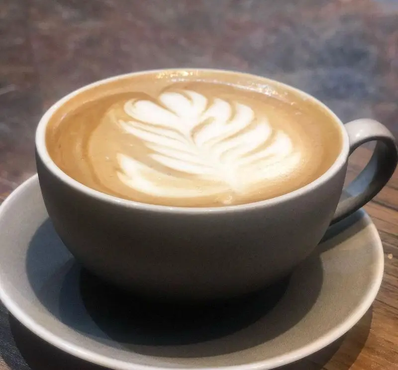 تصویری جذاب از یک فنجان لاته آرت فوق‌العاده در رستوران ایتالیایی ژولی، مکانی عالی برای قهوه‌دوستان و دوستداران غذاهای اصیل.