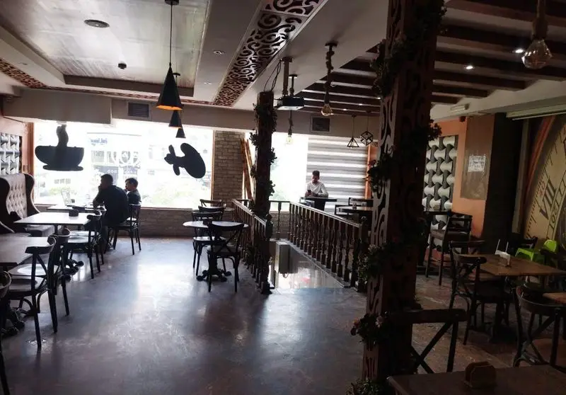 دکوراسیون داخلی شیک و جذاب رستوران ایتالیایی ژولی، با میز و صندلی‌های چوبی، نورپردازی منحصر به فرد و فضای دلنشین برای مشتریان.