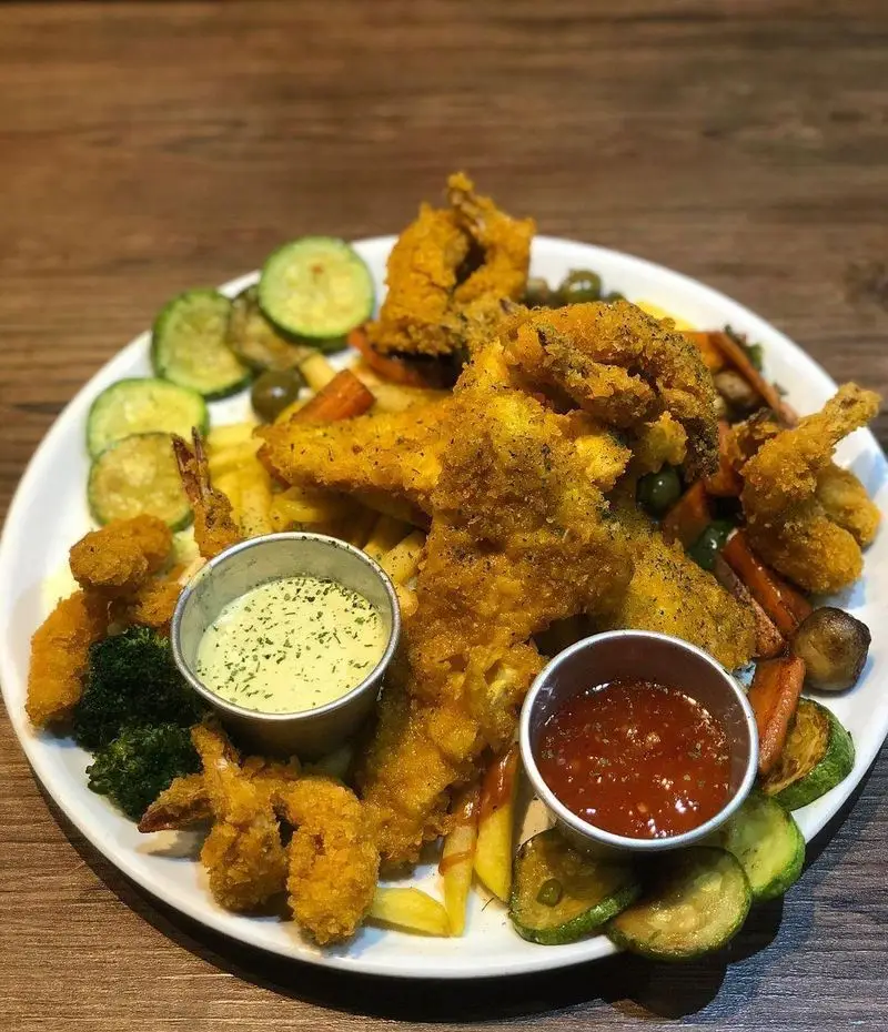 بشقاب بزرگ و خوشمزه از میگو و فیله ماهی سوخاری رستوران ایتالیایی ژولی با سیب‌زمینی، سبزیجات و دو نوع سس.