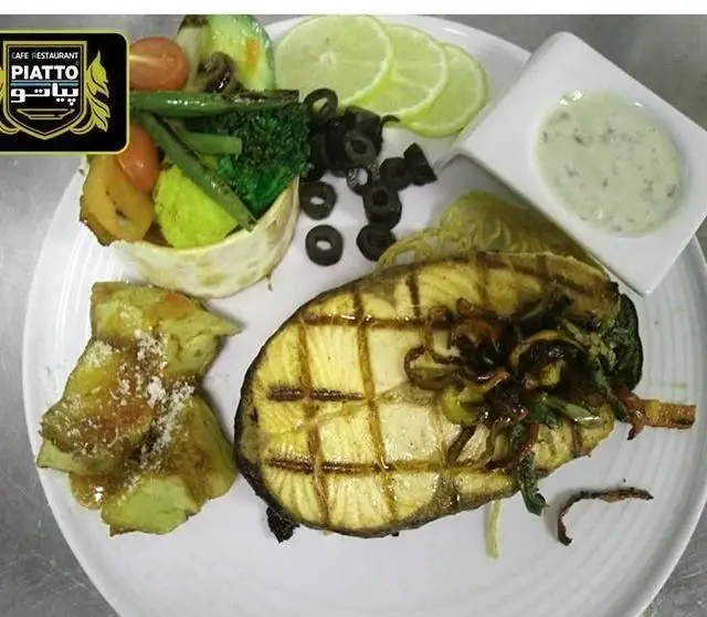 استیک ماهی گریل با دورچین متنوع سبزیجات، سیب زمینی، زیتون و سس مخصوص در کافه رستوران بلوبیسترو.