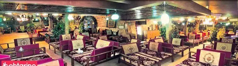 فضای داخلی دنج و سنتی کافه رستوران بلوبیسترو با تخت‌های چوبی، فرش‌های ایرانی و نورپردازی دلنشین برای تجربه غذایی لذت‌بخش.