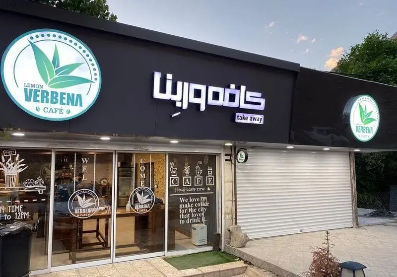 نمای جذاب و مدرن کافه وربنا با تابلوی نئون درخشان، لوگوی برگ سبز لیمو وربنا و سرویس بیرون بر در یک غروب دلنشین.