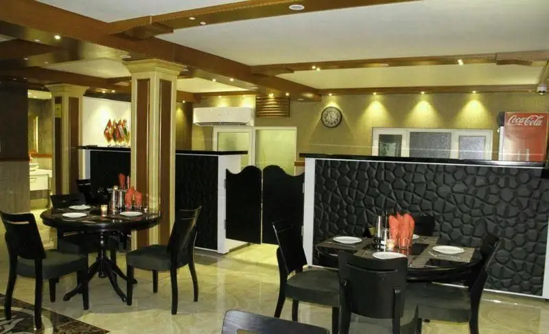 فضای داخلی رستوران ایتالیایی لان چای با میز و صندلی‌های شیک مشکی، دکوراسیون چوبی سقف و نورپردازی گرم، محیطی مدرن و دلپذیر برای تجربه غذا.