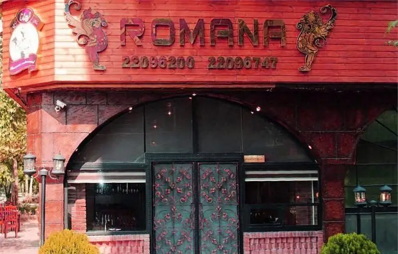 نمای بیرونی و ورودی اصلی رستوران ایتالیایی رومانا، با تابلو نام و شماره تلفن‌های 22096200 و 22096747 و دکوراسیون چوبی و آجری.