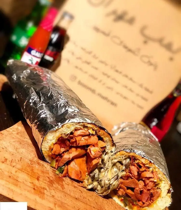 ساندویچ هات داگ و سوسیس بریان پیتزا بریانکده زیتون با پنیر فراوان، پیچیده در فویل؛ یک غذای آماده پرملات و خوشمزه.