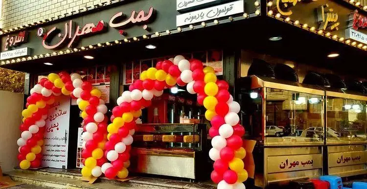 نمای بیرونی پیتزا بریانکده زیتون، با ورودی تزئین شده توسط طاق های بالونی رنگارنگ قرمز، زرد و سفید، محیطی شاد و پرشور را برای استقبال از مشتریان فراهم می کند.