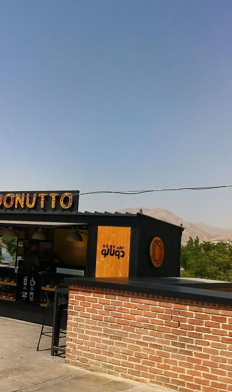 کافه دوناتو در بام لند تهران، مکانی با طراحی مدرن و دلپذیر برای لذت بردن از قهوه و دونات در فضای باز با چشم‌انداز کوهستان.
