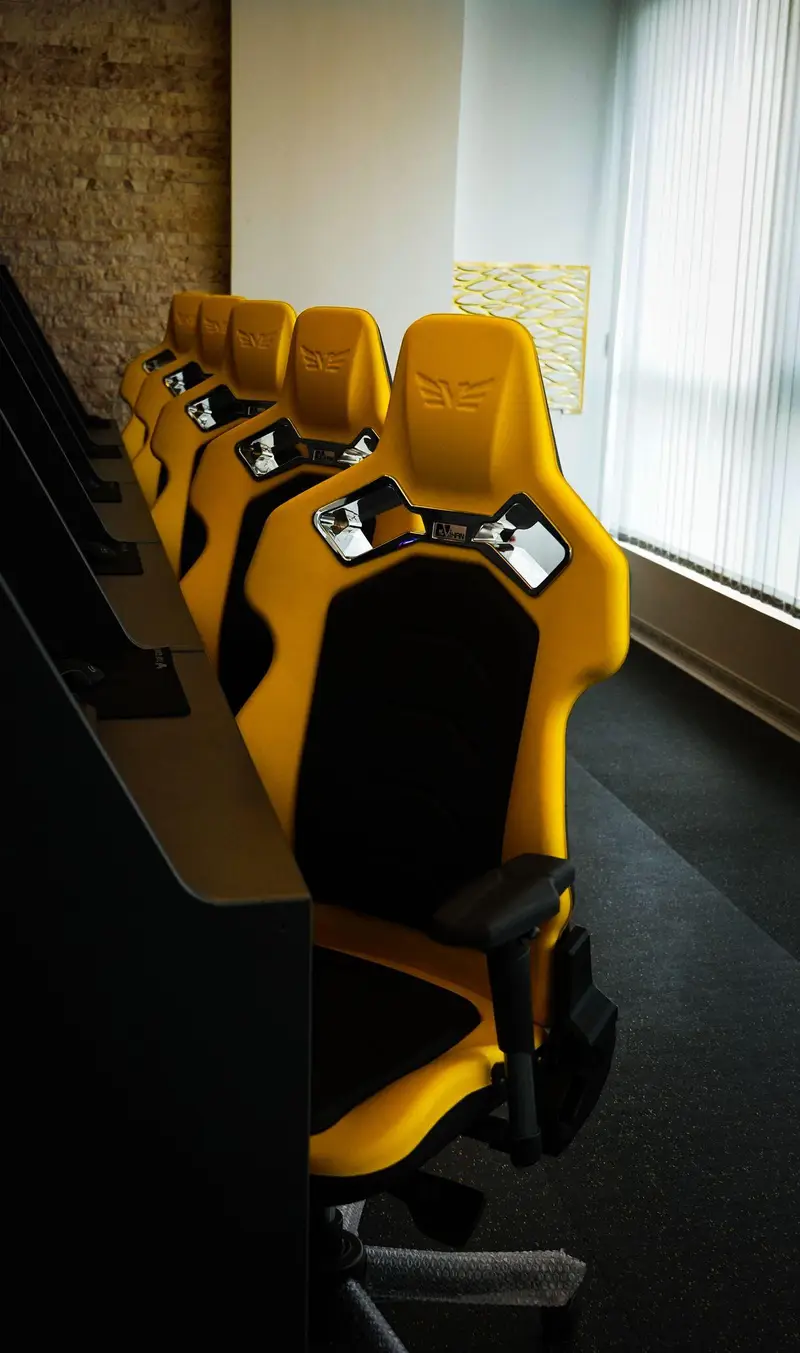 ردیف صندلی‌های گیمینگ ارگونومیک زرد و مشکی با لوگوی SQUAD در سالن اختصاصی گیم سنتر اسکوآد، مکانی پرهیجان برای بازی.