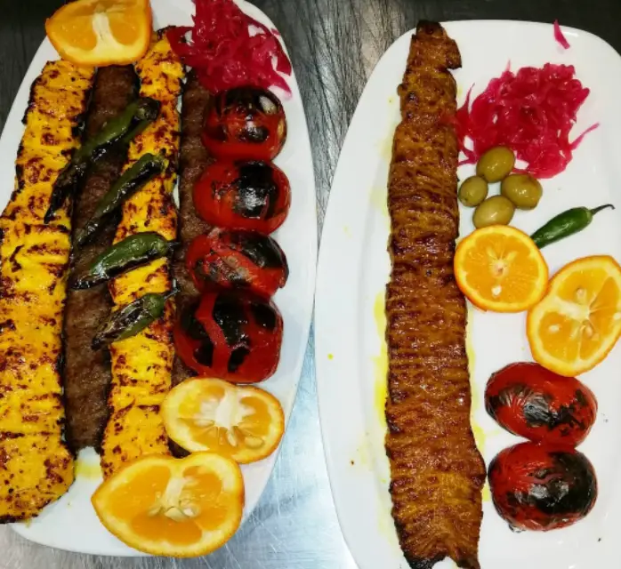 انواع کباب ایرانی لذیذ رستوران سر اشپز شامل جوجه و کوبیده با گوجه کبابی، فلفل، زیتون و نارنج تازه.