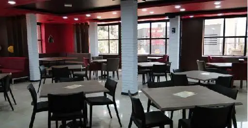 نمایی از فضای داخلی رستوران فست فود آماندا، با دکوراسیون قرمز و مشکی، میز و صندلی‌های چیده شده و محیطی دلنشین برای پذیرایی از مشتریان.