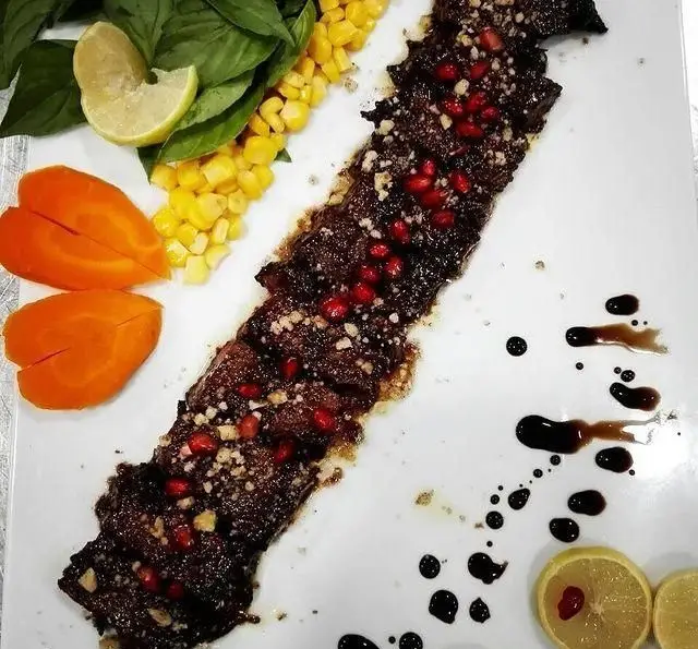 تصویری از خوراک ویژه ایوان رستوران: کباب مجلسی با تزئین انار، گردو، ذرت، لیمو و سبزیجات معطر. طعم اصیل غذای ایرانی را در ایوان تجربه کنید.