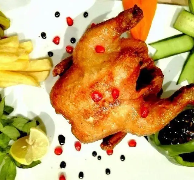 مرغ بریان خوشمزه ایوان رستوران با تزئین دانه های انار، سیب زمینی سرخ کرده، لیمو و سبزیجات تازه، یک انتخاب عالی برای ناهار و شام.
