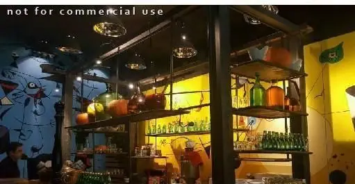 فضای داخلی جذاب فست فود و گریل مم مد استیک هاوس، شامل بار با قفسه‌های پر از بطری‌های رنگارنگ، لیوان‌ها و دیوارهای نقاشی شده هنری.