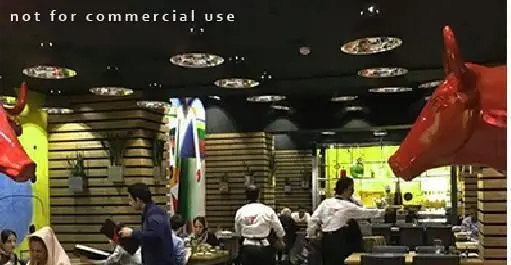 فضای داخلی لوکس و مدرن مم مد استیک هاوس، بهترین فست فود و گریل، با دکوراسیون خاص، مجسمه‌های گاو قرمز و مشتریان شاد.