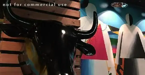 مجسمه گاو مشکی براق و دکوراسیون داخلی مدرن و رنگارنگ مم مد استیک هاوس، محیطی جذاب برای فست فود و گریل.