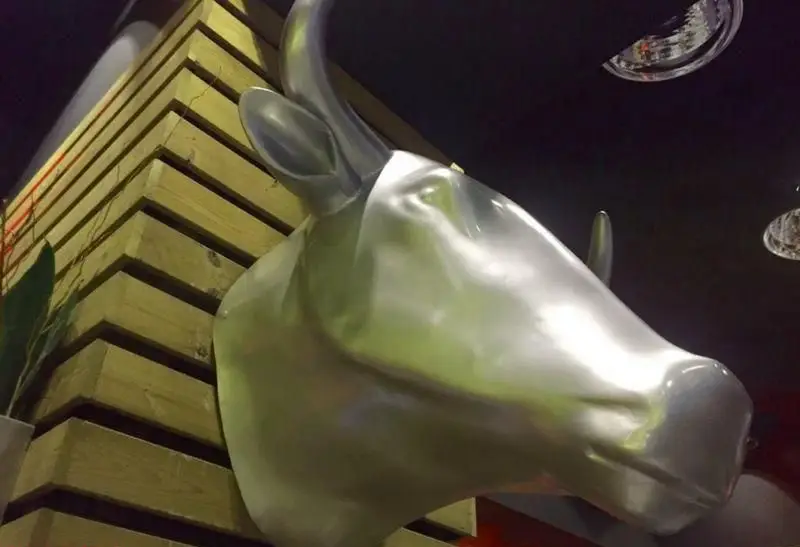 دکوراسیون داخلی مم مد استیک هاوس با مجسمه مدرن گاو فلزی، بازتابی از فضای اصیل و شیک این فست فود و گریل حرفه‌ای.