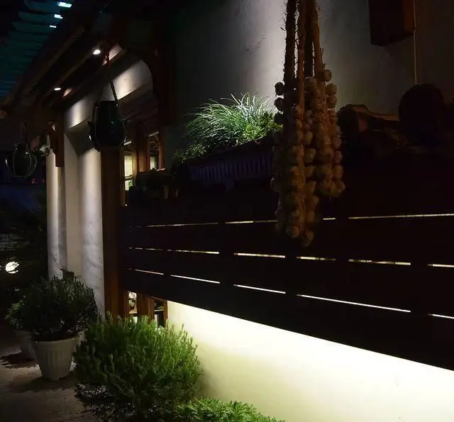 نمای شبانه رستوران شمالی گیله گل با نورپردازی دلنشین، گلدان‌های زیبا، و آویز سیر سنتی، فضایی گرم و دعوت‌کننده را ارائه می‌دهد.