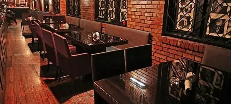 فضای داخلی دنج و شیک کافه خانه هنرمندان با میزهای براق، صندلی‌های راحت، دیوارهای آجری و پنجره‌های خاص. مناسب پاتوق‌های هنری و قرارهای دوستانه.