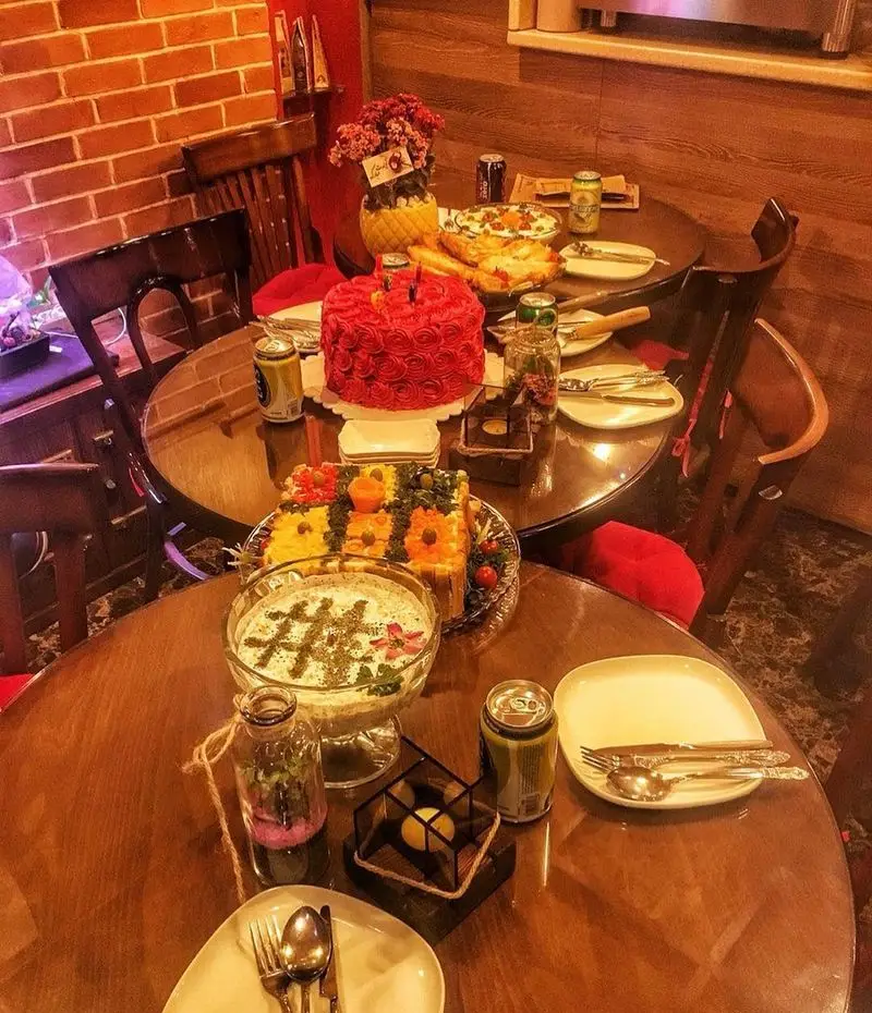 میز آرایی جشن در کافه پندار: کیک رز قرمز، دسر، پیش‌غذا و نوشیدنی‌ها. فضایی دنج و گرم مناسب برای دورهمی و ساخت خاطرات.