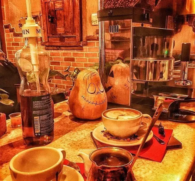 کافه پندار با حال و هوای پاییزی و هالوین: کدو تنبل‌های تزئینی، سیروپ فندق، دستگاه قهوه‌ساز و نوشیدنی‌های گرم در فضایی دنج و صمیمی.