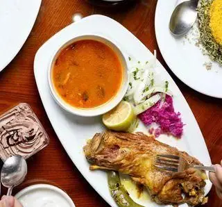 ران گوسفندی بریان مجلسی همراه با خورشت ایرانی، پلو، مخلفات تازه و دسر در رستوران شبستری. بهترین تجربه غذای سنتی ایرانی با کیفیت عالی.