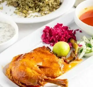 یک پرس مرغ ران طلایی با سس مخصوص، پلوی اعلا، ماست و مخلفات تازه در رستوران شبستری برای یک تجربه غذای ایرانی اصیل.