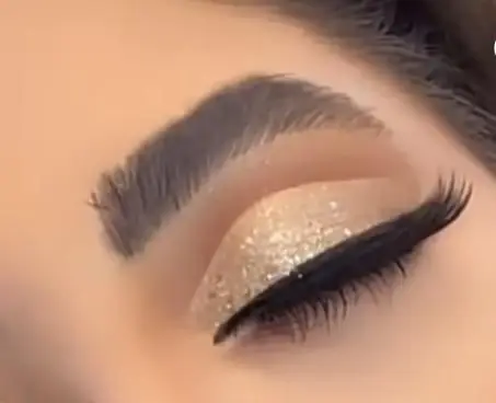 تصویر نزدیک از آرایش چشم با سایه اکلیلی طلایی درخشان، خط چشم مشکی و مژه‌های بلند در سالن آرایش و زیبایی سیندرلا