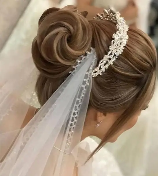 مدل شینیون موی عروس به صورت جمع و بالا همراه با تاج نگین‌دار درخشان و تور سفید، نمونه کار سالن آرایش و زیبایی سیندرلا.