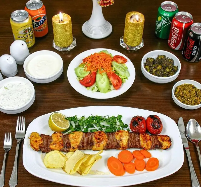 کباب میکس لذیذ رستوران اقدسیه با مخلفات کامل شامل سالاد، سیب‌زمینی، گوجه کبابی و انواع نوشیدنی. غذای ایرانی در تهران.